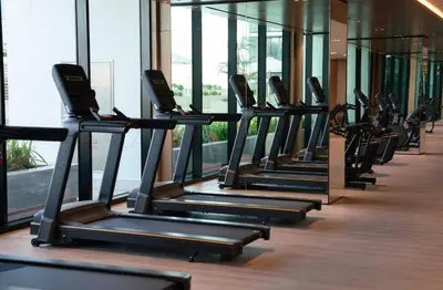 a row of treadmills in a gym at Jvc 1br Oasis Serene Interiors Pool & Parking in Dubai