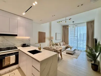 a kitchen and living room with a couch and a table at Jvc 1br Oasis Serene Interiors Pool & Parking in Dubai