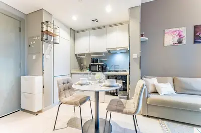 a kitchen and living room with a table and a couch at Dubai Canal and City Views 1BR, Minutes Drive to Burj Khalifa, DAMAC Zada Tower, Business Bay by Deluxe Holiday Homes in Dubai