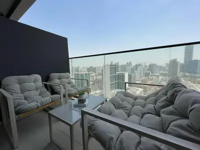 a living room with couches and a view of a city at Bright 1br Jvc Balcony & Free Parking in Dubai
