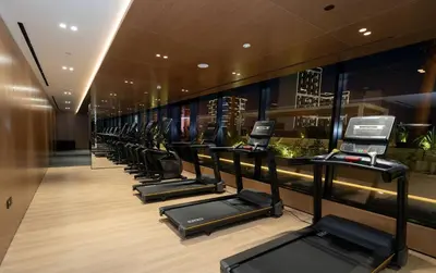 a row of treadmills in a fitness room at Bright 1br Jvc Balcony & Free Parking in Dubai