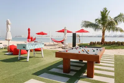 a pool table on a lawn next to the beach at AURA -Direct Seafront 2BR-Palm in Dubai