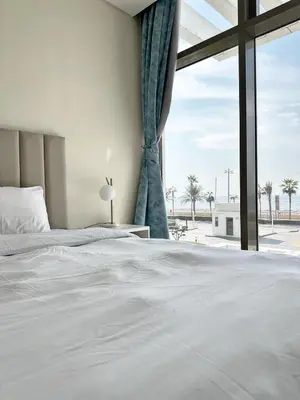 a bedroom with a white bed and a large window at AURA -Direct Seafront 2BR-Palm in Dubai