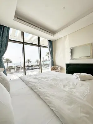a white bedroom with a large bed and a large window at AURA -Direct Seafront 2BR-Palm in Dubai