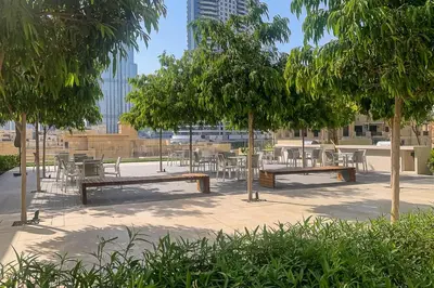 a park with benches and tables and trees at Frank Porter - Burj Royale in Dubai