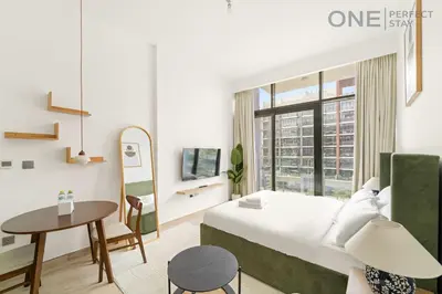 a bedroom with a bed and a table and a desk at Cozy Studio Apartment in Meydan in Dubai