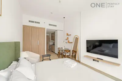a bedroom with a bed and a television on a wall at Cozy Studio Apartment in Meydan in Dubai