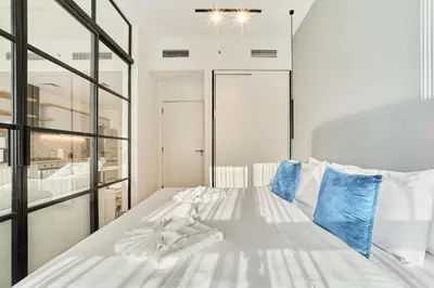 a bedroom with a white bed with blue pillows at Cozy 1BR in Socio Dubai Hills Near Mall and Park in Dubai