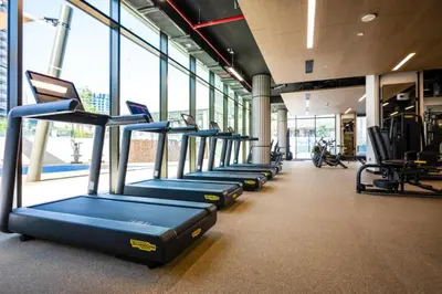 a row of treadmills in a gym with windows at High Floor Burj and Canal View Business Bay in Dubai