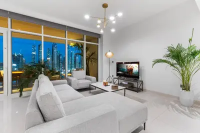 a living room with a white couch and a tv at Full Sea View & Dubai Skyline - 4BR LUX Beachfront in Dubai