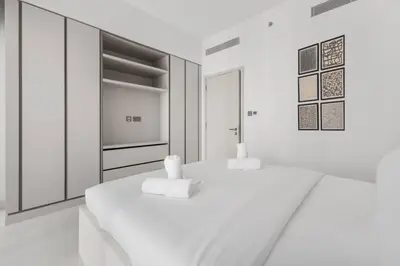 a white bedroom with two beds and a tv at Full Sea View & Dubai Skyline - 4BR LUX Beachfront in Dubai