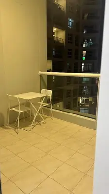 a table and chairs on a balcony with a window at RKOkeys in Dubai