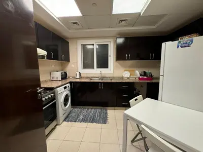 a kitchen with black cabinets and a white refrigerator at RKOkeys in Dubai