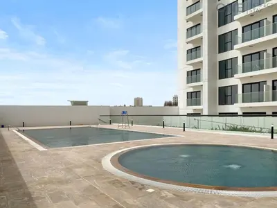 a swimming pool in front of a building at 1BR with Balcony Near Metro Station in Dubai