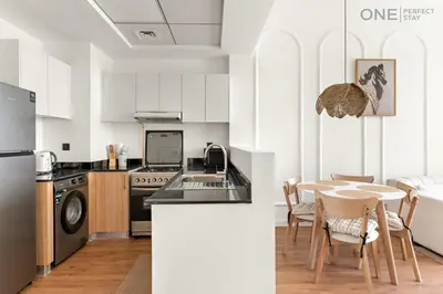 a kitchen and dining room with a table and a refrigerator at 1BR with Balcony Near Metro Station in Dubai
