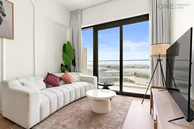 a living room with a white couch and a tv at 1BR with Balcony Near Metro Station in Dubai
