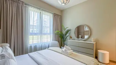 a bedroom with a bed and a mirror and a window at Peaceful 1BR in La Serine, Lush Garden Views - 1AB02 in Dubai