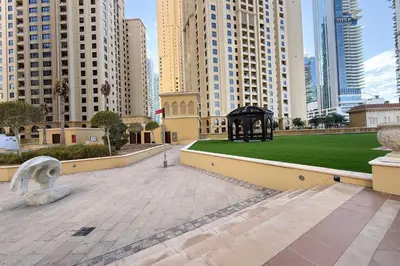 a park in the middle of a city with tall buildings at Cozy Beachside 1-bedroom in Murjan in Dubai