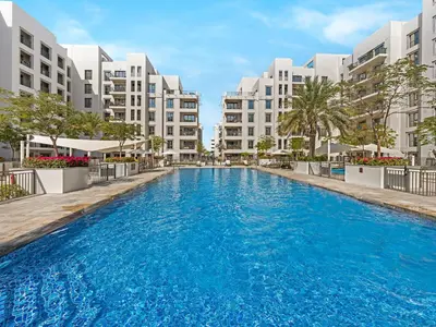 a swimming pool in front of some apartment buildings at The Town Square Suite Luxury 2BR Near Qudra Lake in Dubai