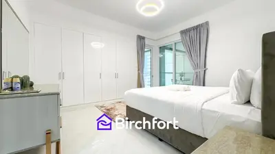 a white bedroom with a bed and a kitchen at Stylish Stay Steps from the Marina in Dubai