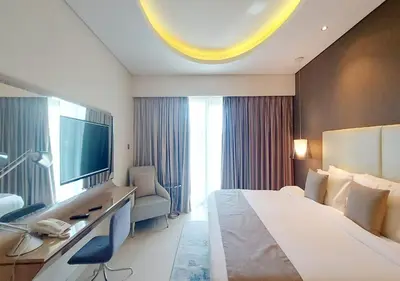 a hotel room with a bed and a desk and a television at Damac Paramount Tower in Dubai