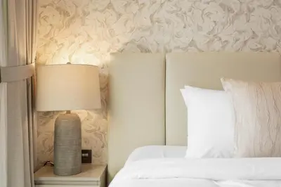 a bedroom with a bed and a lamp on a night stand at Sleek 1Bedroom with Burj Khalifa view in Peninsula in Dubai