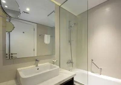 a white bathroom with a sink and a shower at Modern Living DAMAC with Balcony & Waterfront Views in Dubai