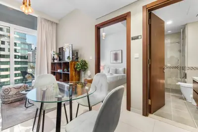 a living room with a glass table and chairs and a bathroom at Cozy 1 BR in the Center - 5 mins to Burj Khalifa in Dubai