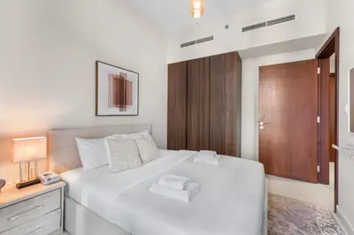a bedroom with a white bed and a wooden door at Cozy 1 BR in the Center - 5 mins to Burj Khalifa in Dubai