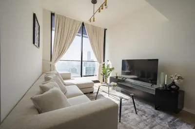 a living room with white furniture and a large window at Brand New Luxurious - Modern 1BR - Pool - Gym in Dubai