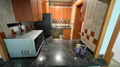 a small kitchen with a counter and a refrigerator at 1 Bedroom in Dubai Marina opp Dmcc metro station in Dubai