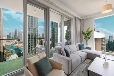 a living room with a couch and large windows at Stunning Downtown 4BR Sky High Luxury Apartment with Fountain Views in Dubai