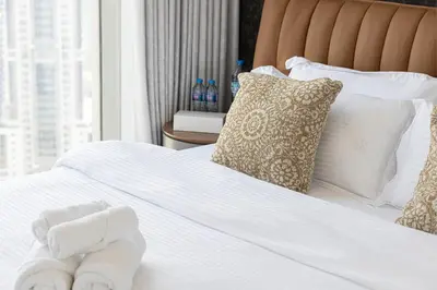 a bed with white sheets and pillows and a window at Stunning Downtown 4BR Sky High Luxury Apartment with Fountain Views in Dubai