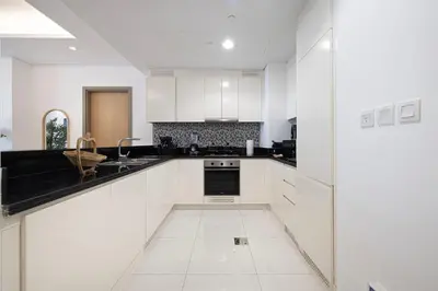 a kitchen with white cabinets and black counter tops at 3BR in Paramount with Panoramic Infinity Pool in Dubai