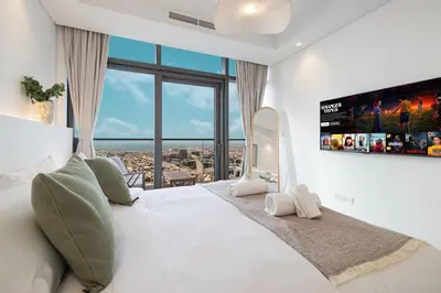 a bedroom with a large white bed with a large window at 3BR in Paramount with Panoramic Infinity Pool in Dubai