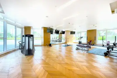 a large room with a gym with wooden floors and large windows at High-Rise Studio Near the Golf Club and Mall with a Community View,Damac Hills Artesia Tower D, Dubailand by Deluxe Holiday Homes in Dubai