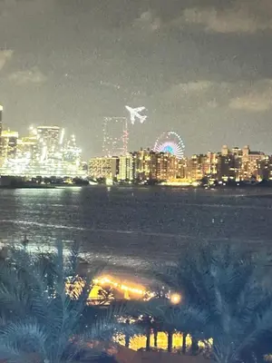 a city skyline at night with a plane flying over at Fleur Star Apartments in Dubai
