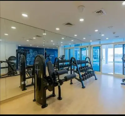 a gym with several tread machines and a mirror at Fleur Star Apartments in Dubai