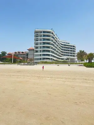 a person walking on the beach with a building in the background at Fleur Star Apartments in Dubai