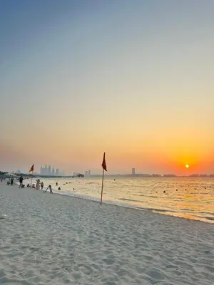 a beach with a flag in the sand at sunset at Fleur Star Apartments in Dubai