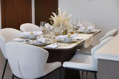 a dining room table with white chairs and a table set with wine glasses at Stay in Modern Elegance 4BR with Pool Gym and Boulevard Views in Dubai