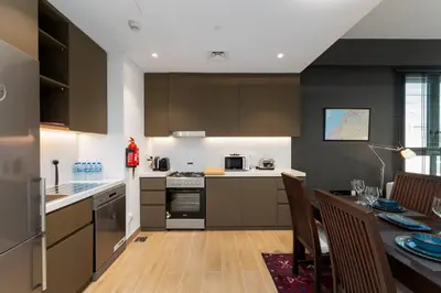 a kitchen with brown cabinets and a dining table at La Sirene 1, Port De La Mer - Mint Stay in Dubai