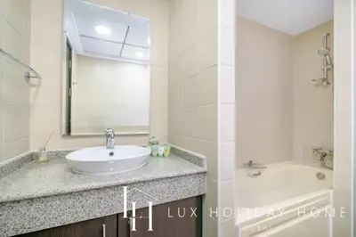 a bathroom with a sink and a tub and a mirror at LUX The Dubai Marina View Suite 2 in Dubai
