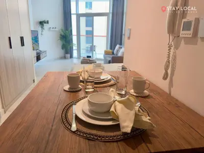 a dining room table with cups and plates on it at Urban Living with Balcony, Pool, and Quick Access to Burj Khalifa in Dubai