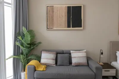 a living room with a gray couch and a plant at Urban Living with Balcony, Pool, and Quick Access to Burj Khalifa in Dubai