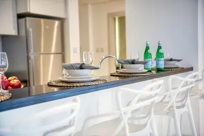 a kitchen with a counter with wine bottles and chairs at The Smart Concierge - Damac Heights in Dubai