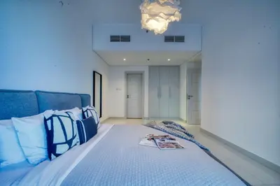 a bedroom with a large bed with blue pillows at The Smart Concierge - Damac Heights in Dubai