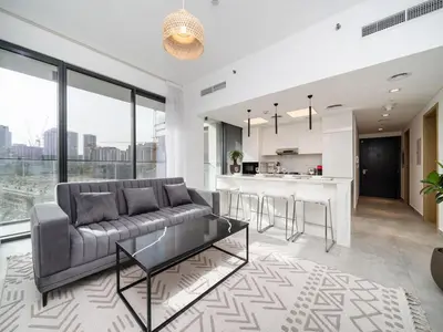 a living room with a couch and a kitchen at Stylish JVC 1 Bed with Wraparound Balcony in Dubai