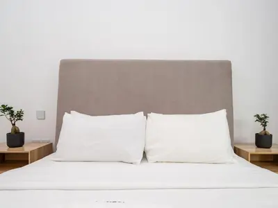 a white bed with two pillows and two tables at Stylish JVC 1 Bed with Wraparound Balcony in Dubai