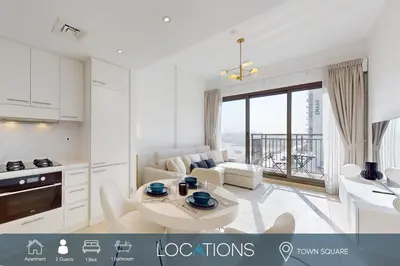 a white kitchen and living room with a table at UNA Tower - Peaceful One Bedroom in Townsquare in Dubai